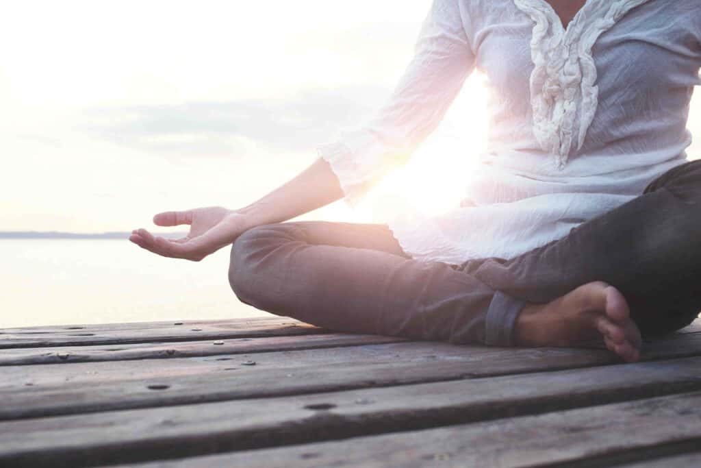 Woman meditating on pier at lake