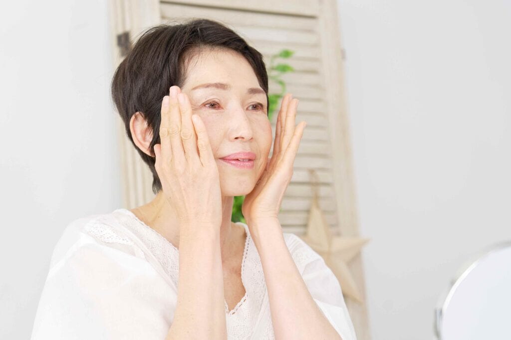 Woman puts on face cream in front of mirror.